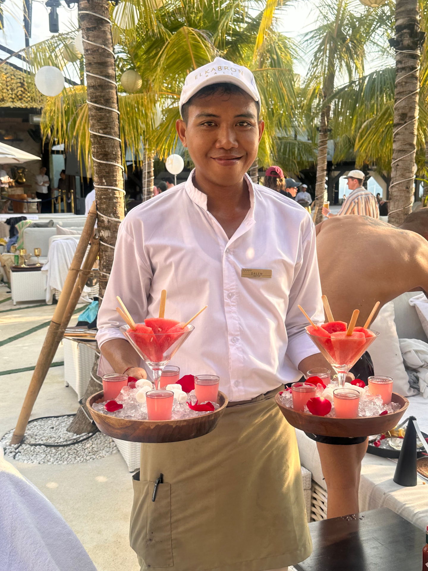 Beach club waiter carrying trays of watermelon and chilled cocktails