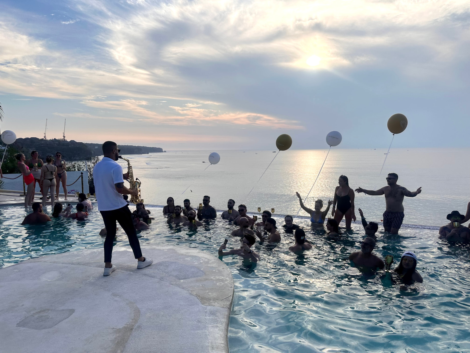Saxophonist playing beside a cliffside infinity pool at sunset in Bali