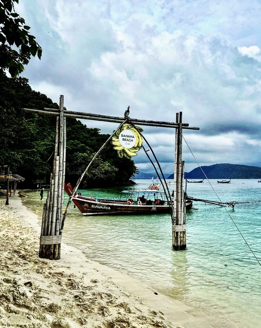 Longtail boat moored off Banana Beach with bamboo swing frame on the sand