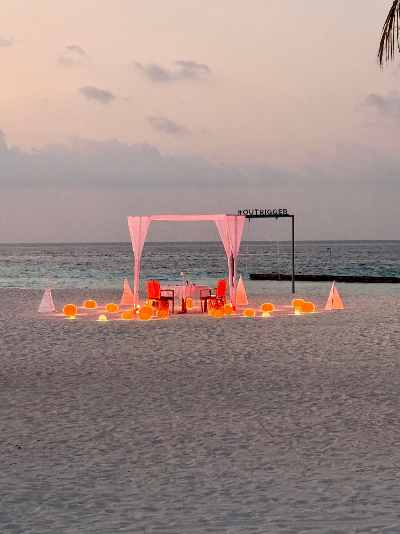 Private candlelit dinner set up on the sand at sunset in the Maldives