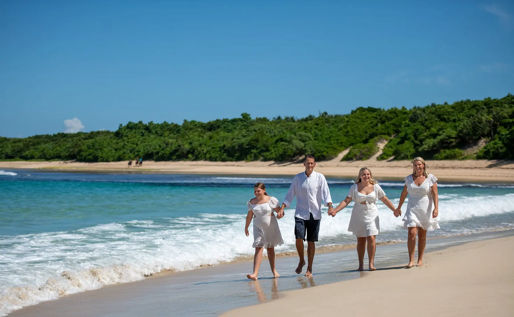 A family walking the shoreline at Natadola Beach, Fiji