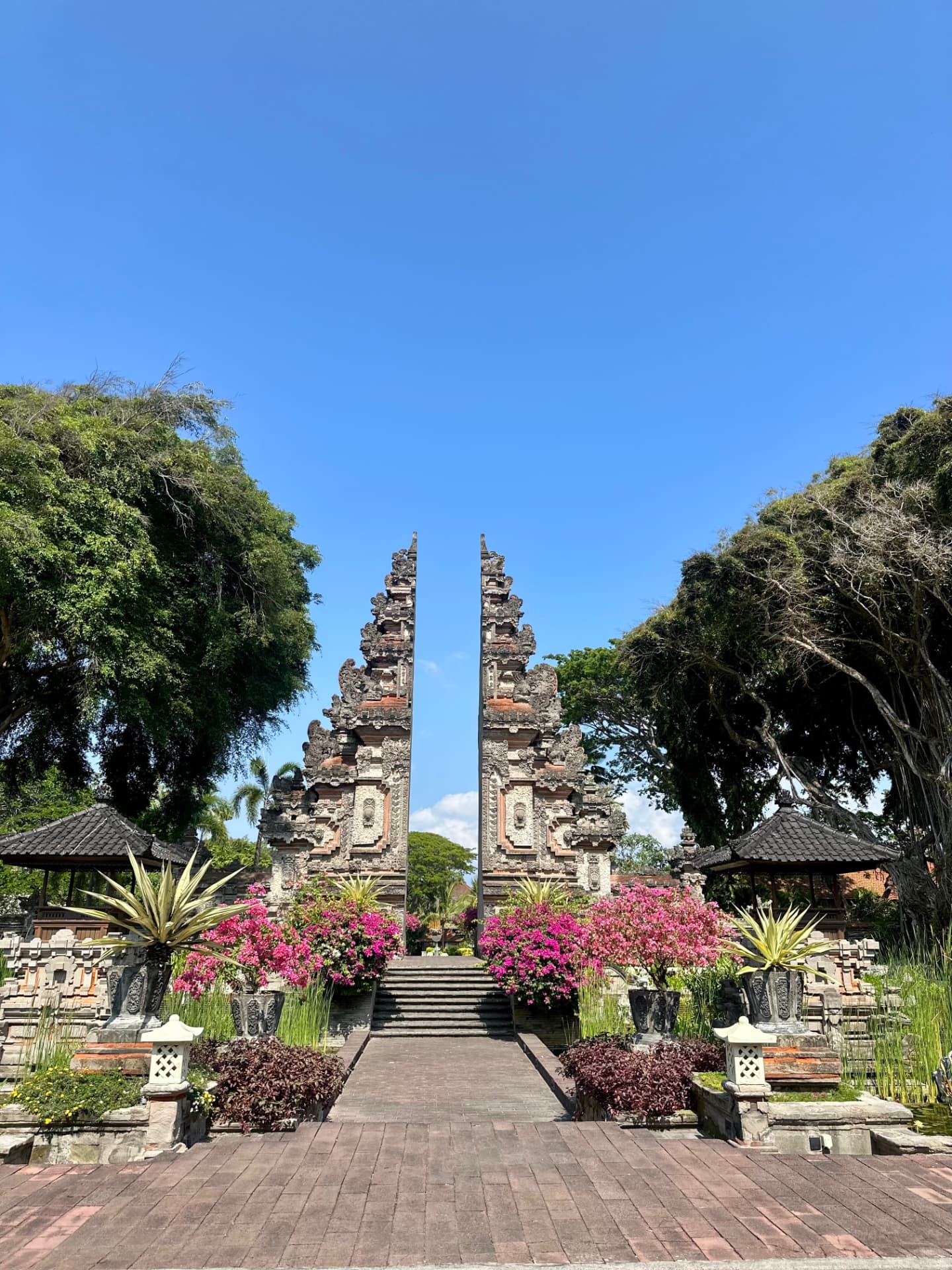 Split Balinese candi bentar temple gate framed by bougainvillea